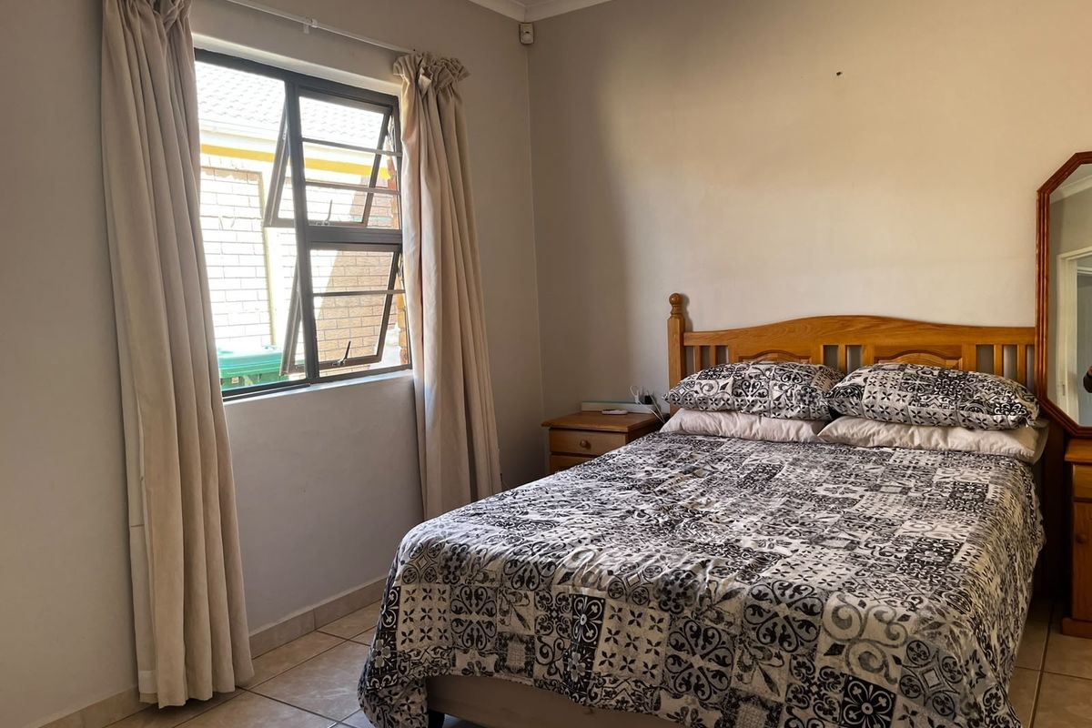 A functional bedroom featuring tiled flooring and a window with aluminium frames, offering a neutral base for potential interior updates.
