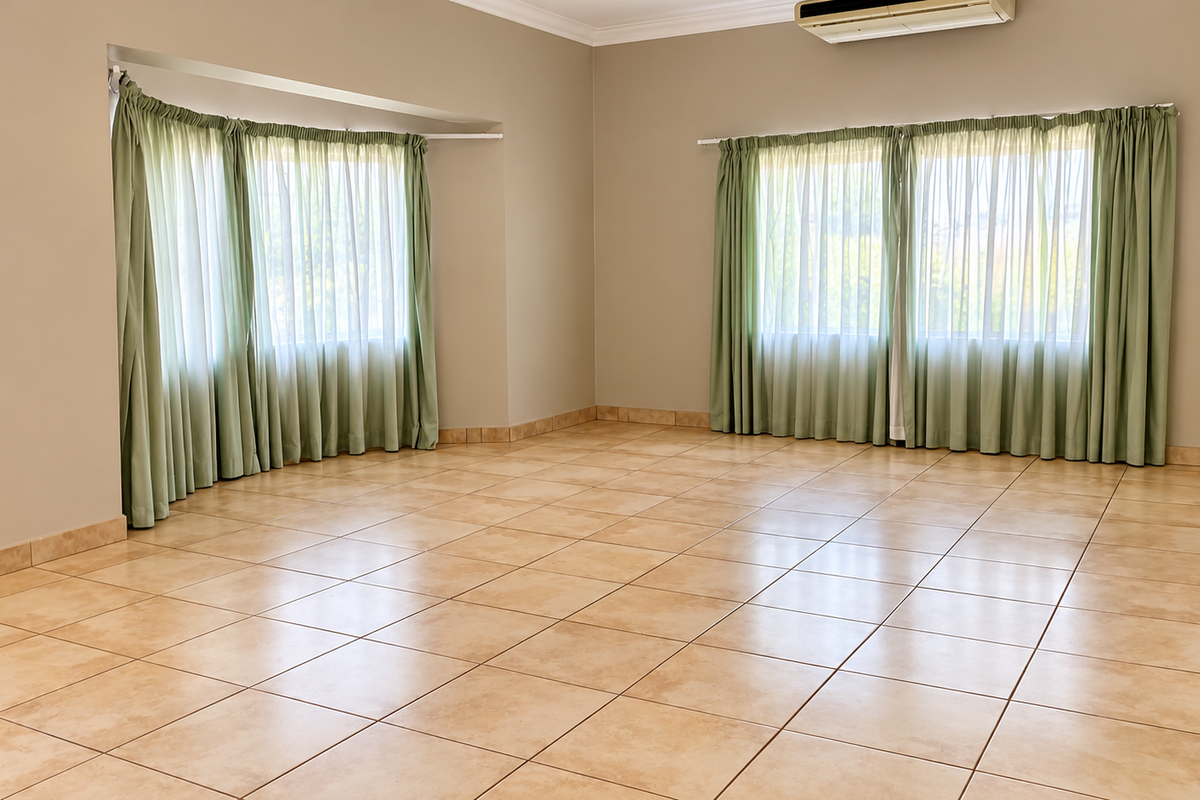 Spacious, light-filled living area featuring neutral walls, ceramic tile flooring, and wall-mounted air conditioning, offering a versatile blank canvas for interior design.