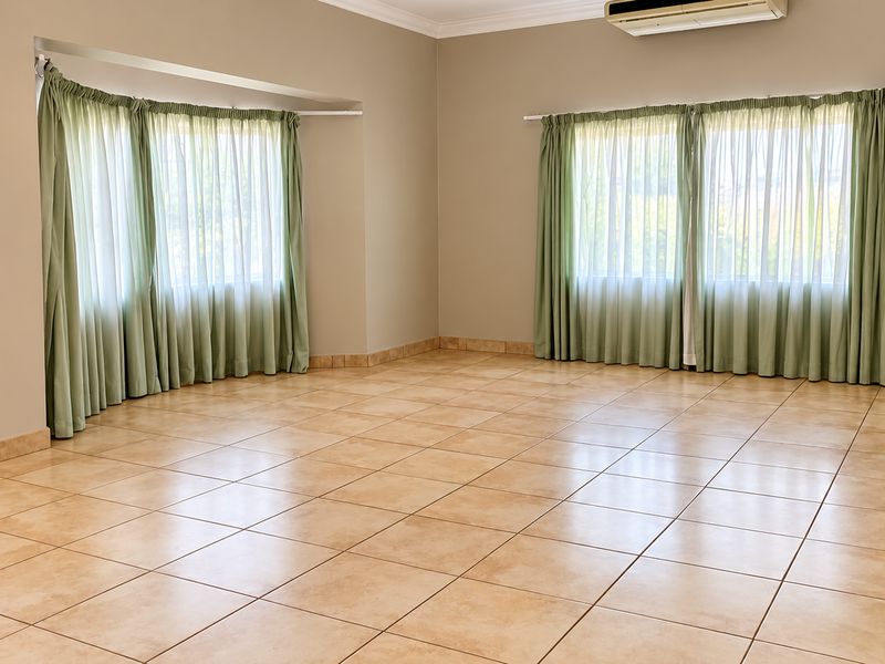 Spacious, light-filled living area featuring neutral walls, ceramic tile flooring, and wall-mounted air conditioning, offering a versatile blank canvas for interior design.