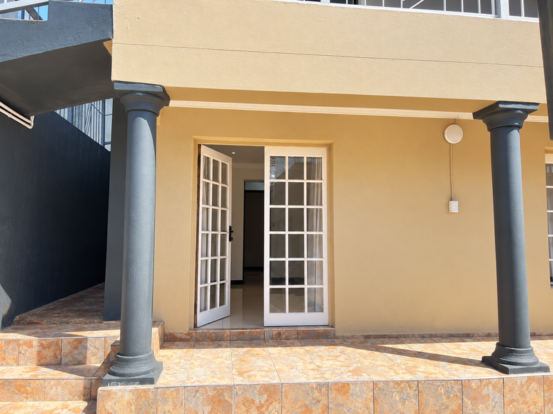A covered patio area featuring tiled flooring, decorative columns, and white-framed french doors leading into the interior of the property.