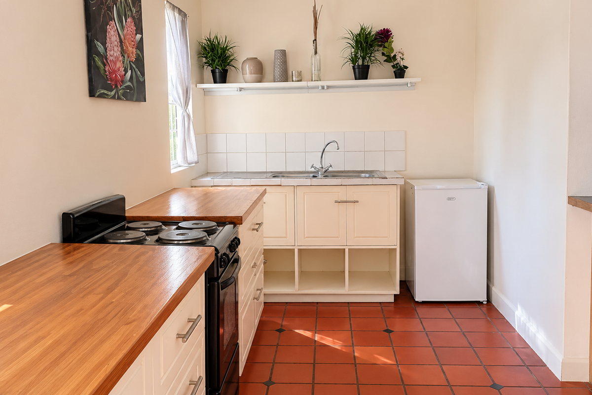 A functional kitchen featuring wooden countertops, built-in cabinetry, a stainless steel sink, and a tiled backsplash with classic ceramic floor tiles.