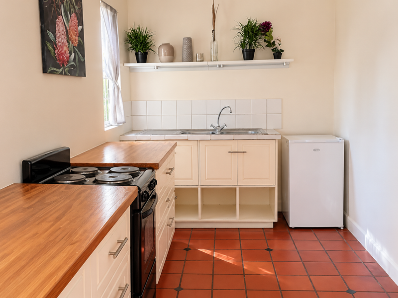 A functional kitchen featuring wooden countertops, built-in cabinetry, a stainless steel sink, and a tiled backsplash with classic ceramic floor tiles.