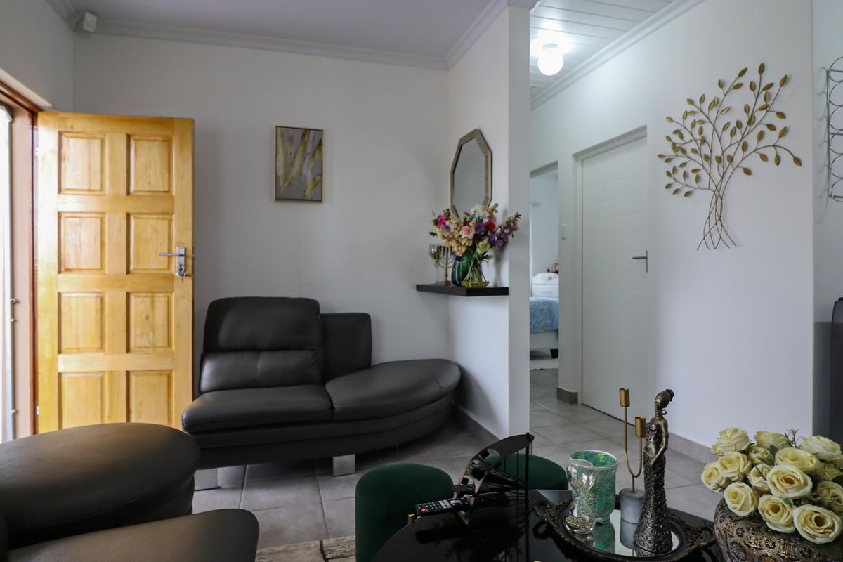 A view of a living area featuring tiled flooring, a solid wood door, and access to an adjacent bedroom.