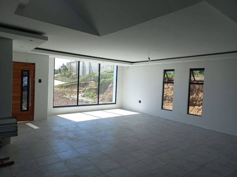Spacious open-plan living area featuring large floor-to-ceiling windows, tiled flooring, and modern recessed ceiling details, offering a bright and airy atmosphere.