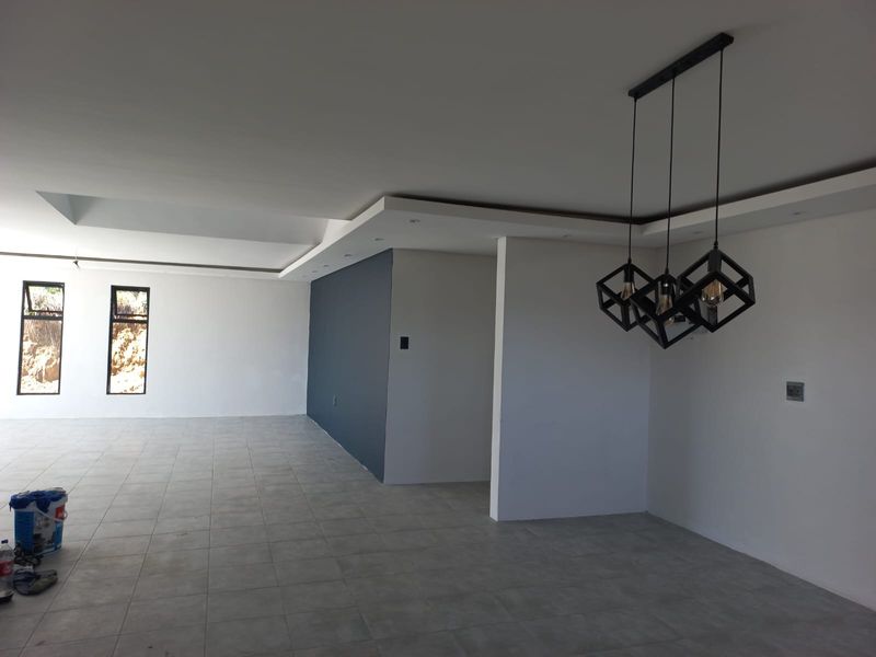 Spacious open-plan living area featuring modern tiled flooring, recessed ceiling details, and contemporary geometric pendant lighting.