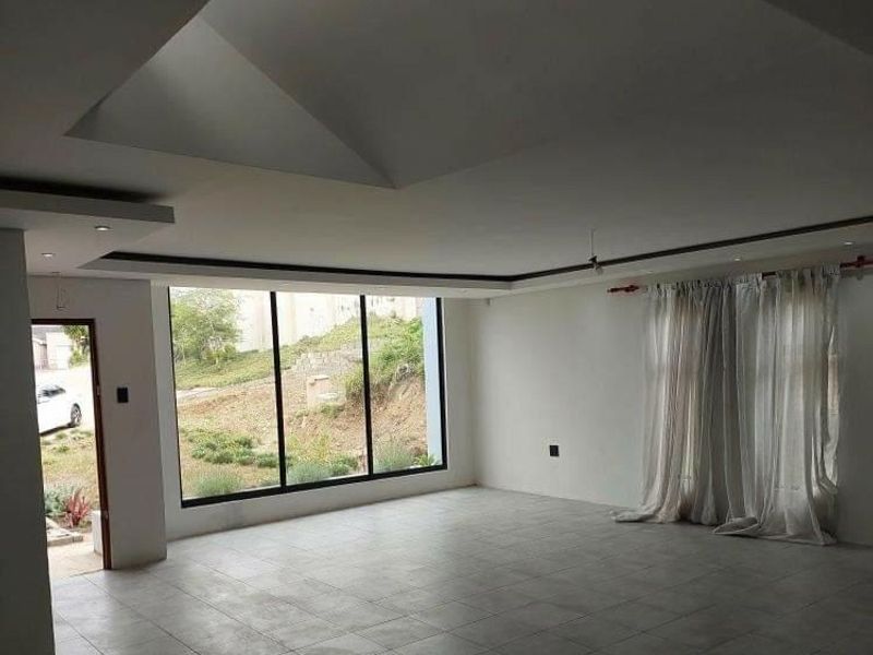 Spacious open-plan living area featuring large floor-to-ceiling windows, recessed ceiling details, and neutral tiled flooring.