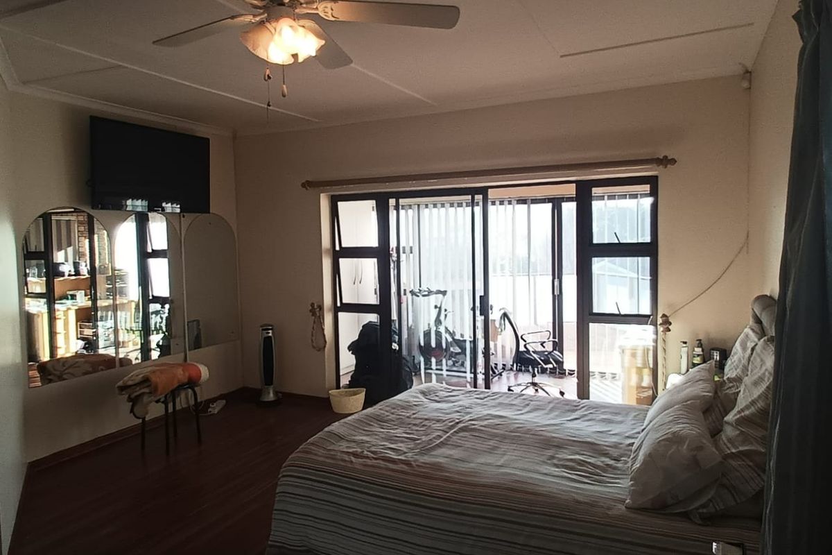 Spacious bedroom featuring laminate flooring, a ceiling fan, and large sliding glass doors providing access to an outdoor patio area.