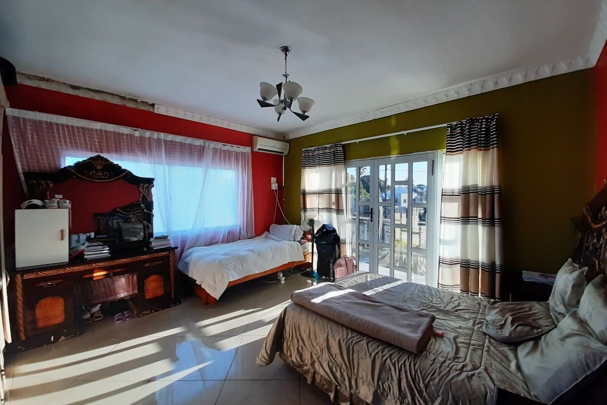 Spacious bedroom featuring tiled flooring, crown molding, a wall-mounted air conditioning unit, and glass panel doors leading to an outdoor area.