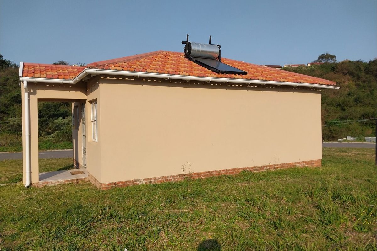 Side view of a single-story house featuring a tiled roof, solar water heating system, and a covered entrance area.