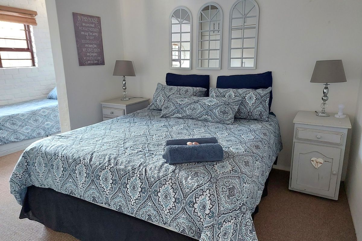 A bedroom featuring a double bed, neutral walls, and an adjoining alcove area with a window.