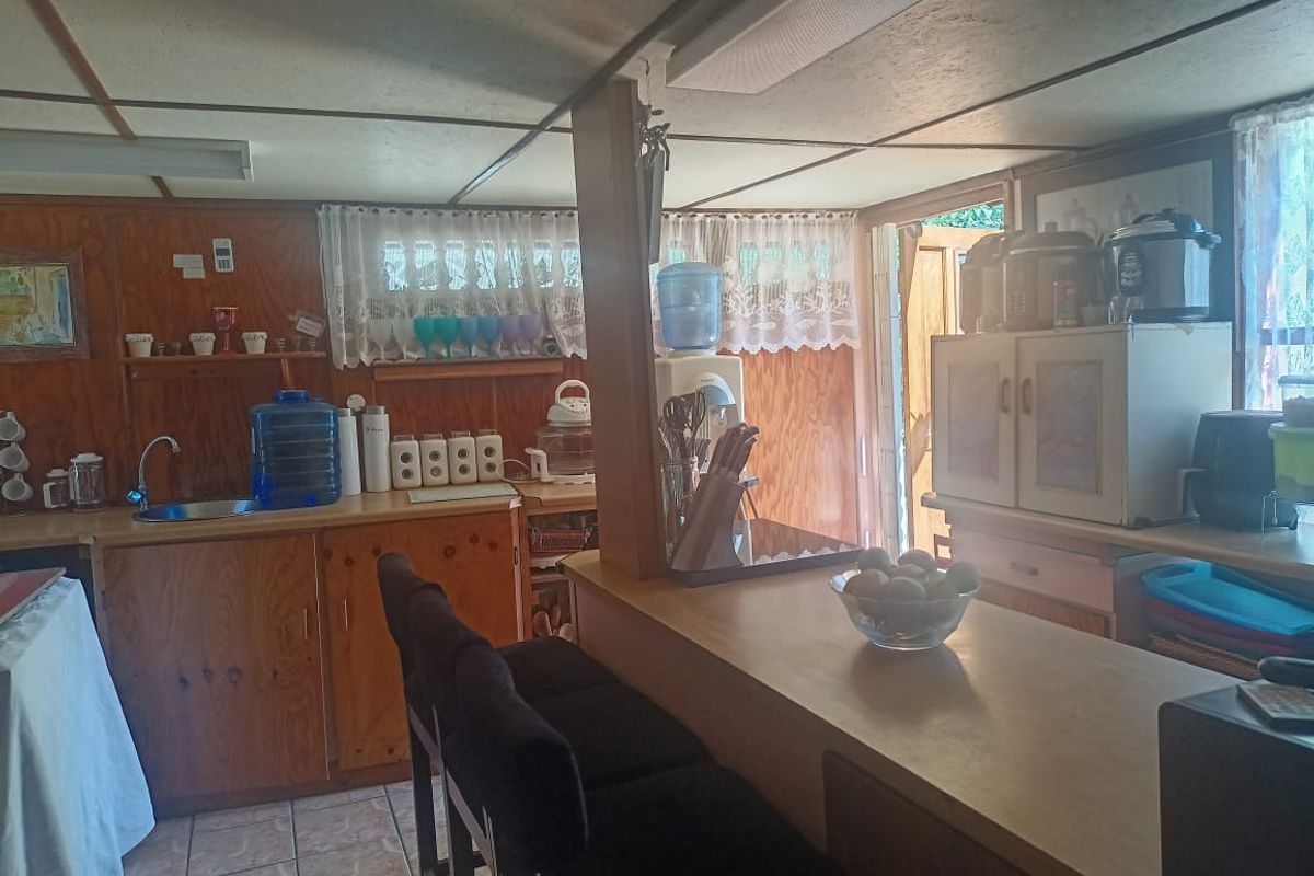 A dated kitchen area featuring wood-paneled walls, a breakfast bar, and tiled flooring with direct access to the exterior.