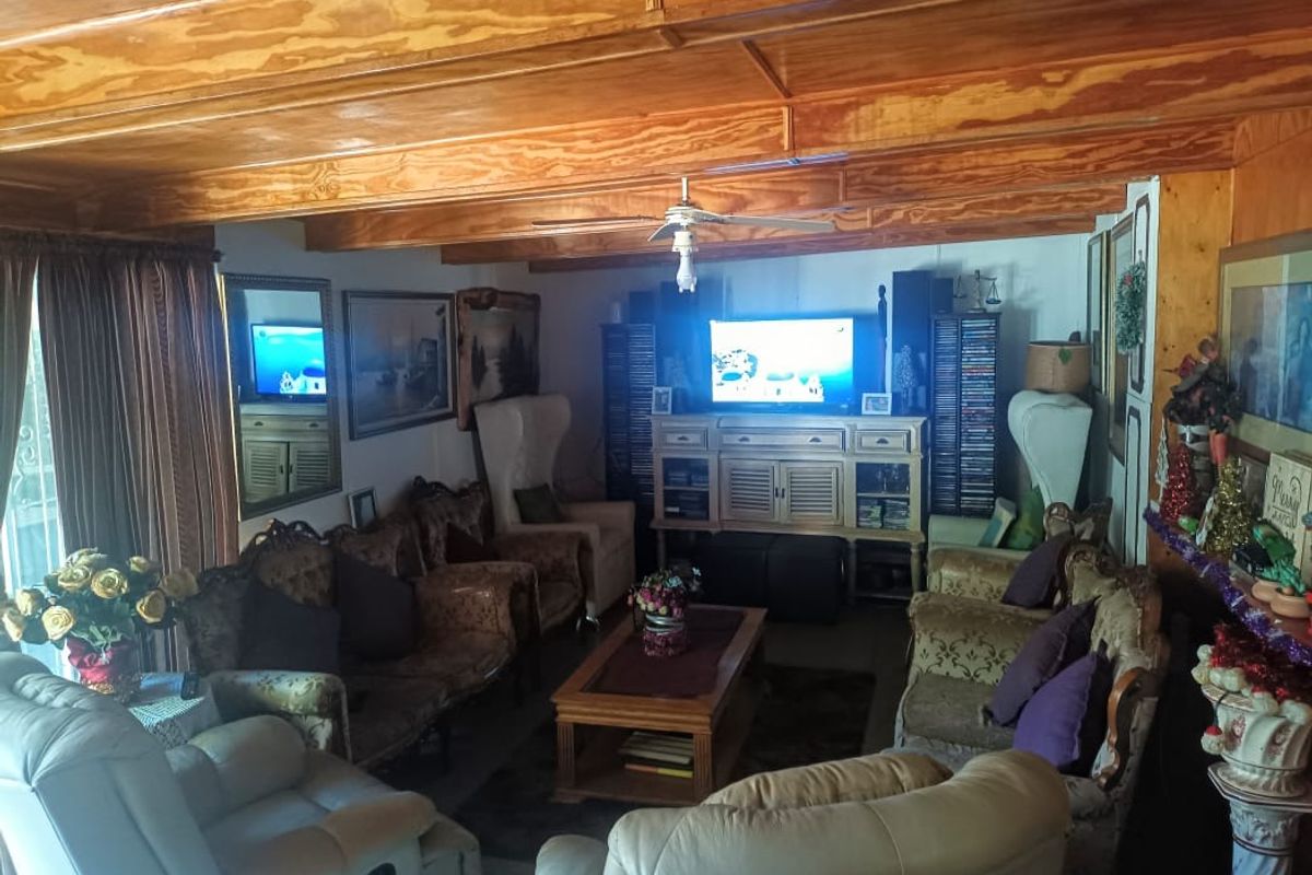 A cozy living room featuring exposed wooden ceiling beams and traditional wood paneling, creating a warm and rustic atmosphere.