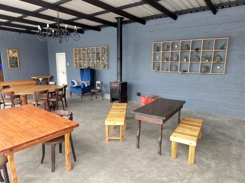 Spacious covered patio area featuring a wood-burning stove, exposed beam ceiling, and polished concrete flooring, suitable for outdoor entertainment.