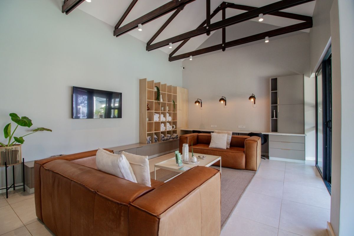 Spacious living area featuring high vaulted ceilings with exposed timber trusses, built-in cabinetry, and large sliding glass doors leading to the exterior.