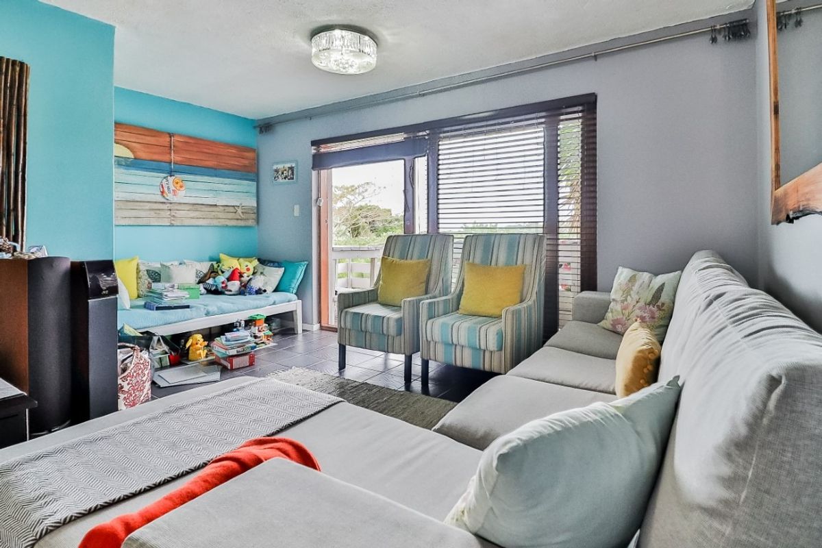 A living room featuring tiled flooring and sliding glass doors that provide access to an outdoor patio area.