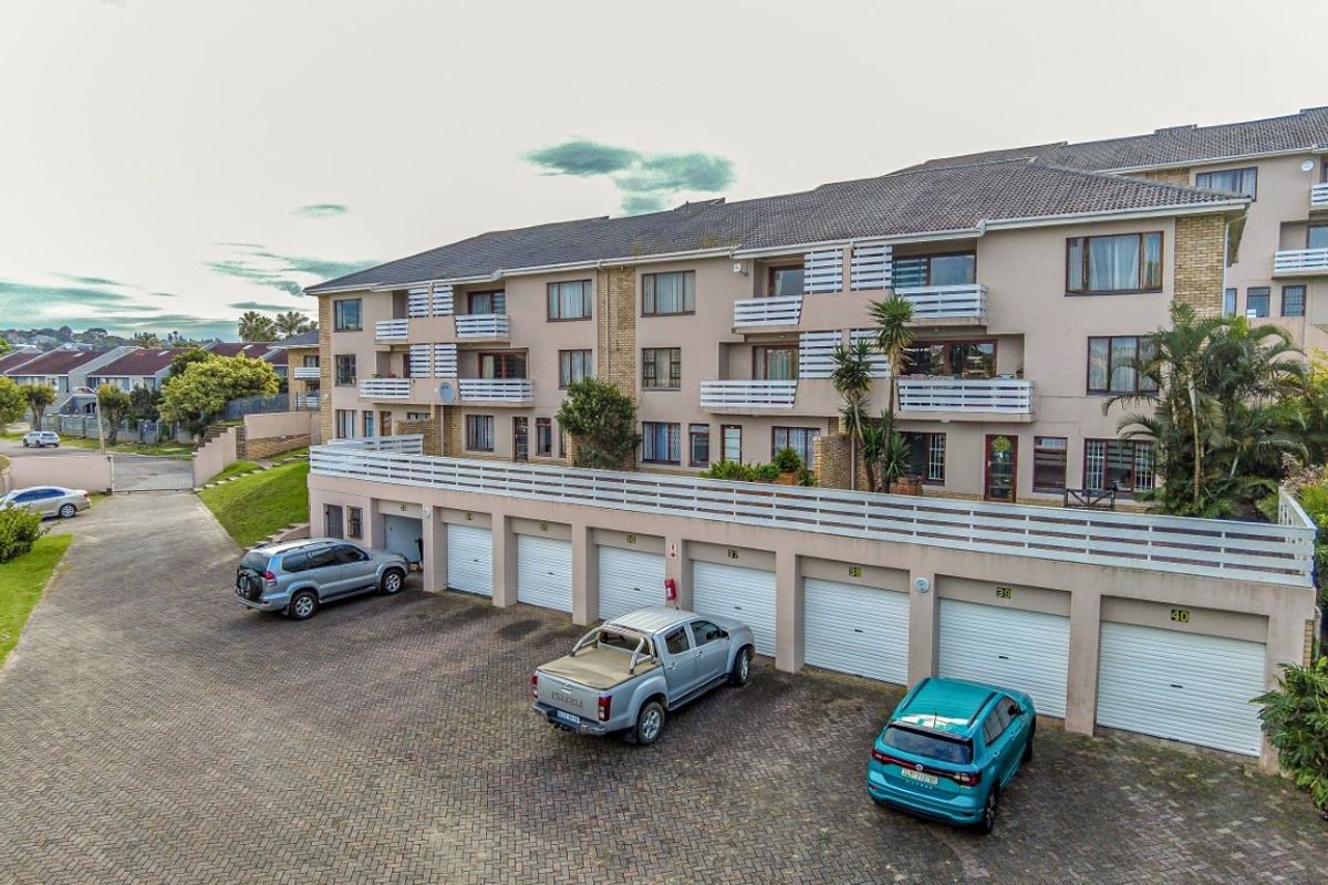 Aerial view of a multi-story townhouse complex featuring a row of ground-level garages and upper-level balconies with white railings.