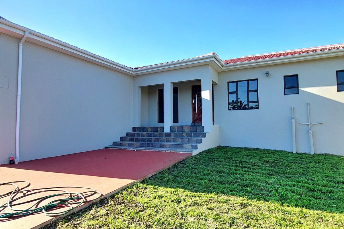 Rear view of the property featuring a tiled patio area, concrete steps leading to the entrance, and an attached garage.