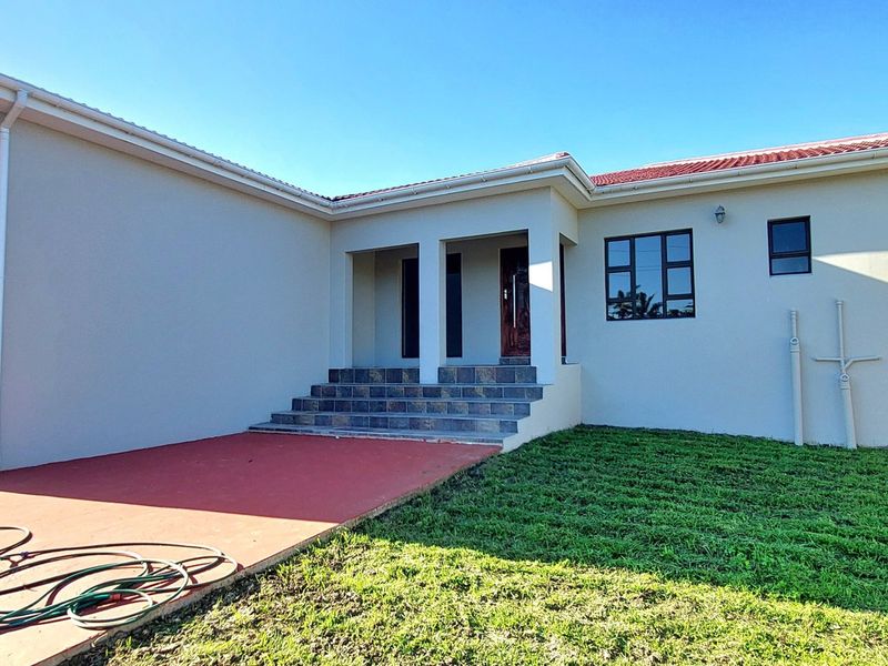Rear view of the property featuring a tiled patio area, concrete steps leading to the entrance, and an attached garage.