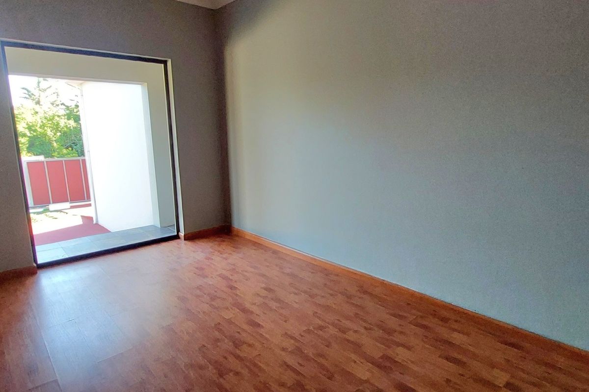 An empty bedroom featuring laminate flooring and a sliding glass door providing access to an outdoor area.