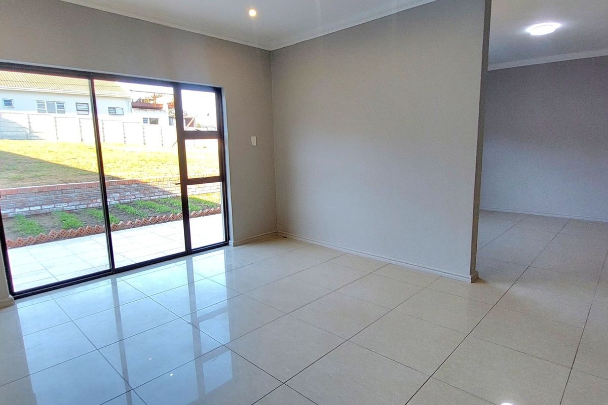 A bright, empty living area featuring large sliding glass doors leading to the exterior, neutral walls, and polished tile flooring throughout.