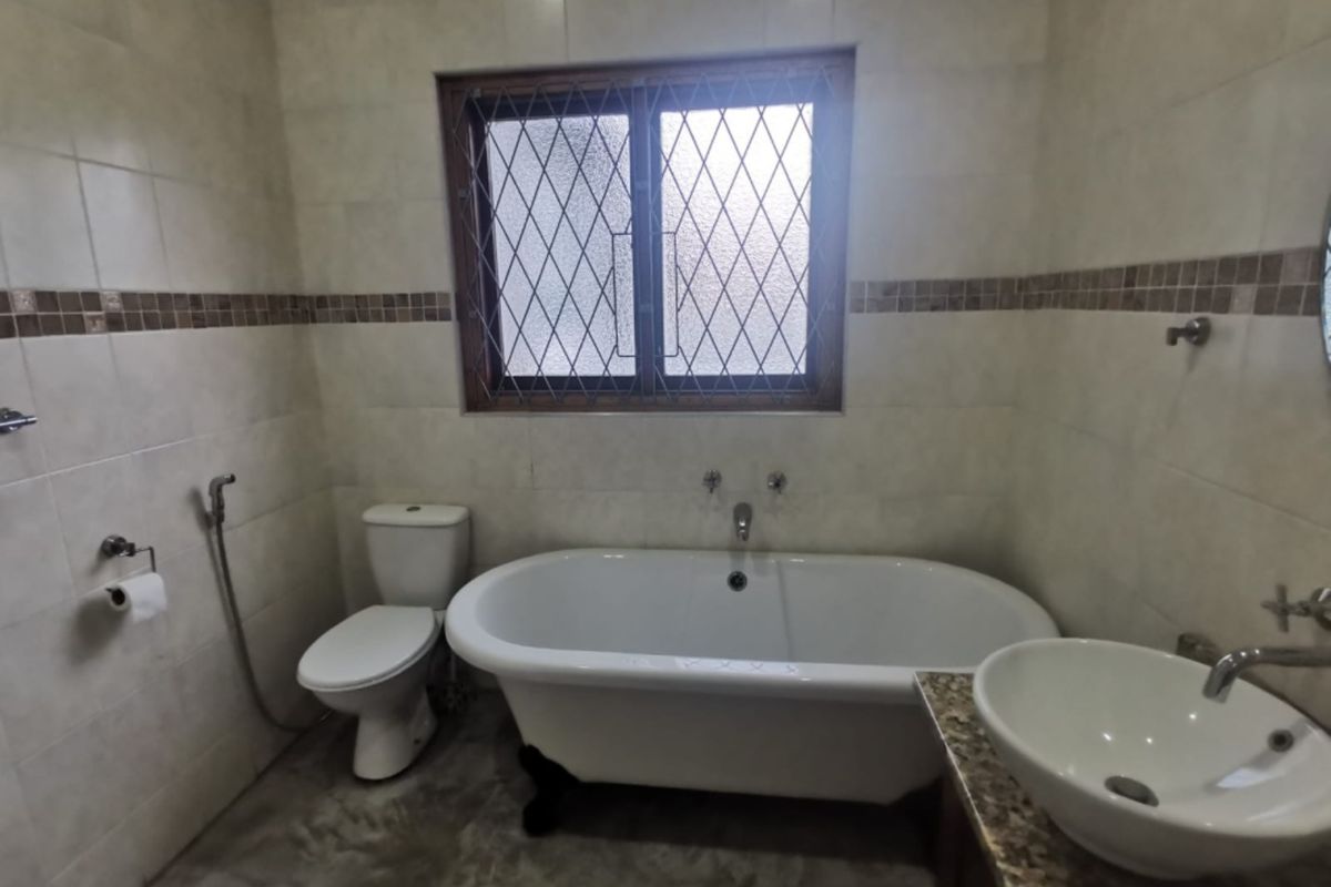 A functional bathroom featuring a freestanding bathtub, a modern vessel sink on a granite vanity, and a toilet with a bidet spray attachment.