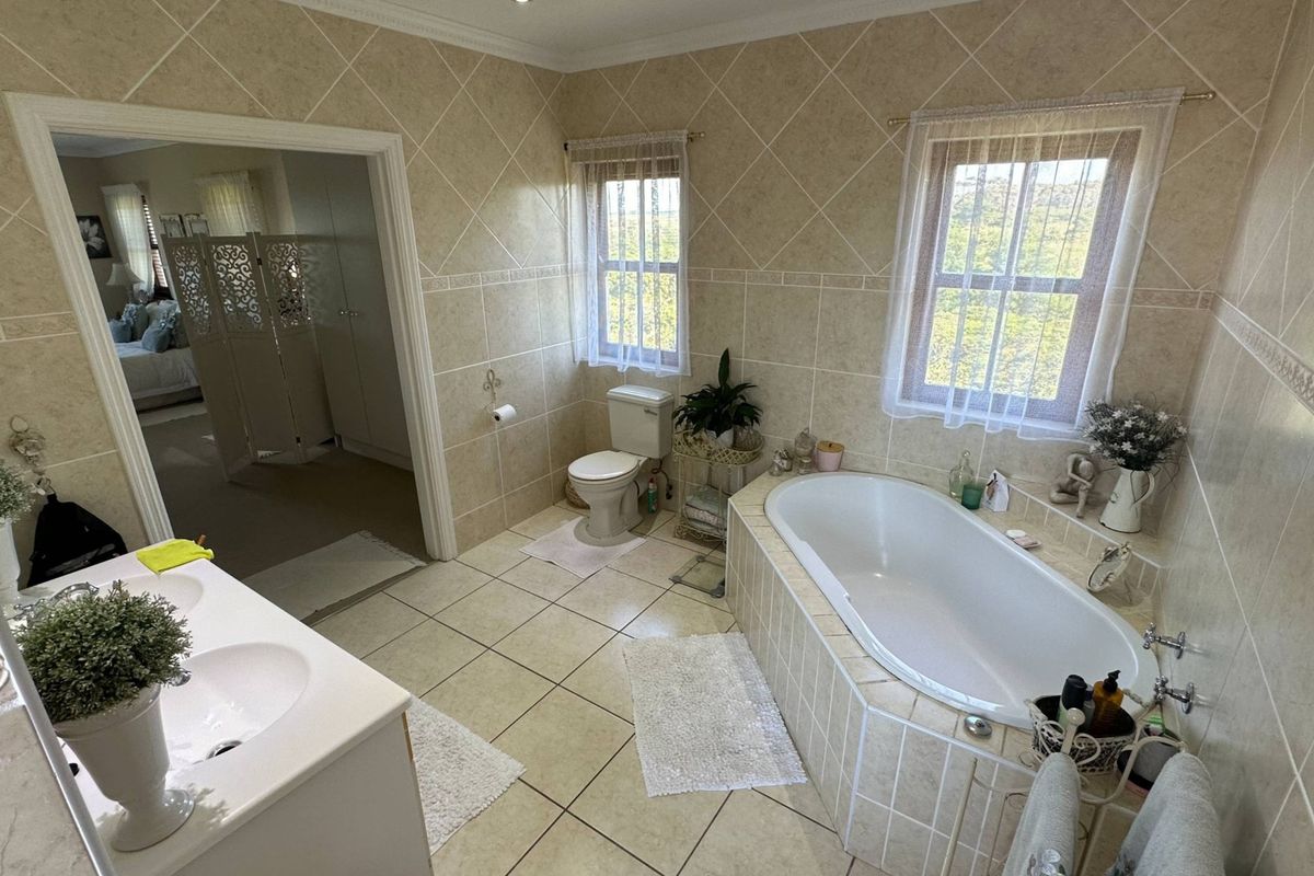 A spacious bathroom featuring a built-in bathtub, tiled walls and flooring, and a vanity unit with dual sinks.