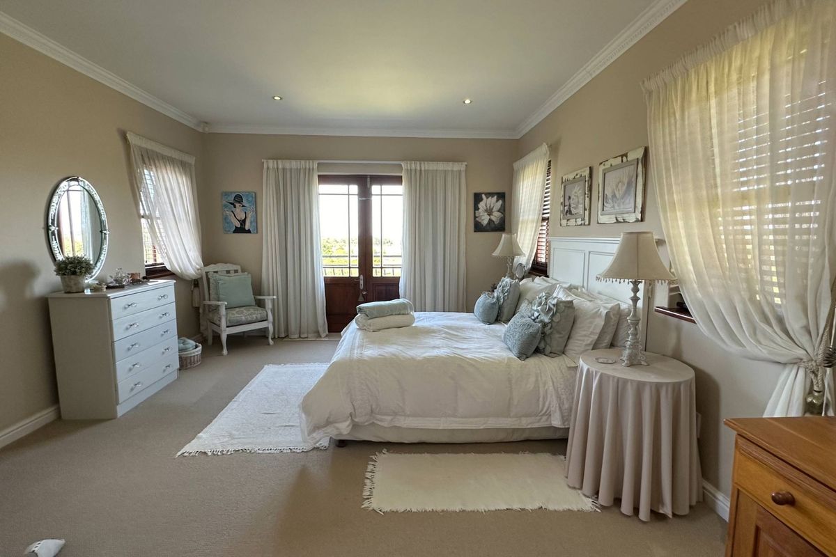 Spacious bedroom featuring neutral carpeting, crown molding, recessed lighting, and double doors leading to an outdoor area.