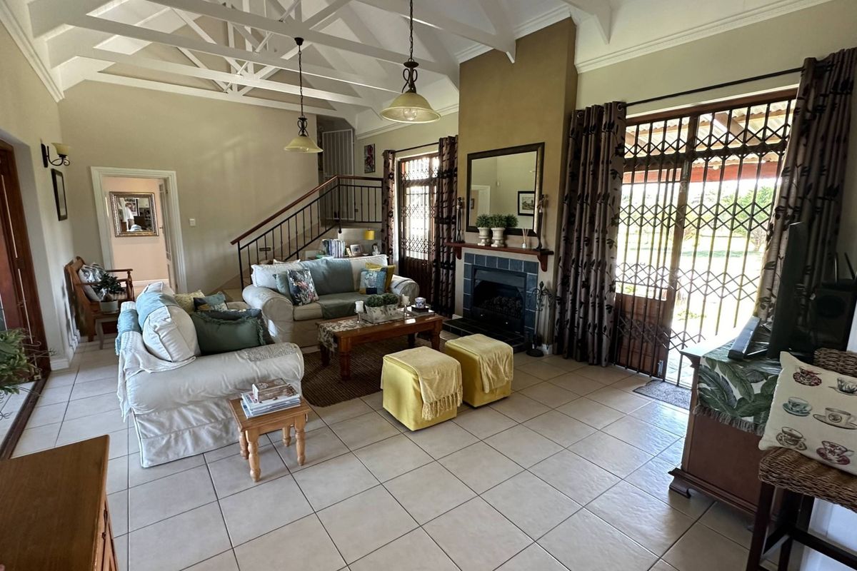 Spacious living room featuring high vaulted ceilings with exposed trusses, a central fireplace, and direct access to the outdoor area through security gates.