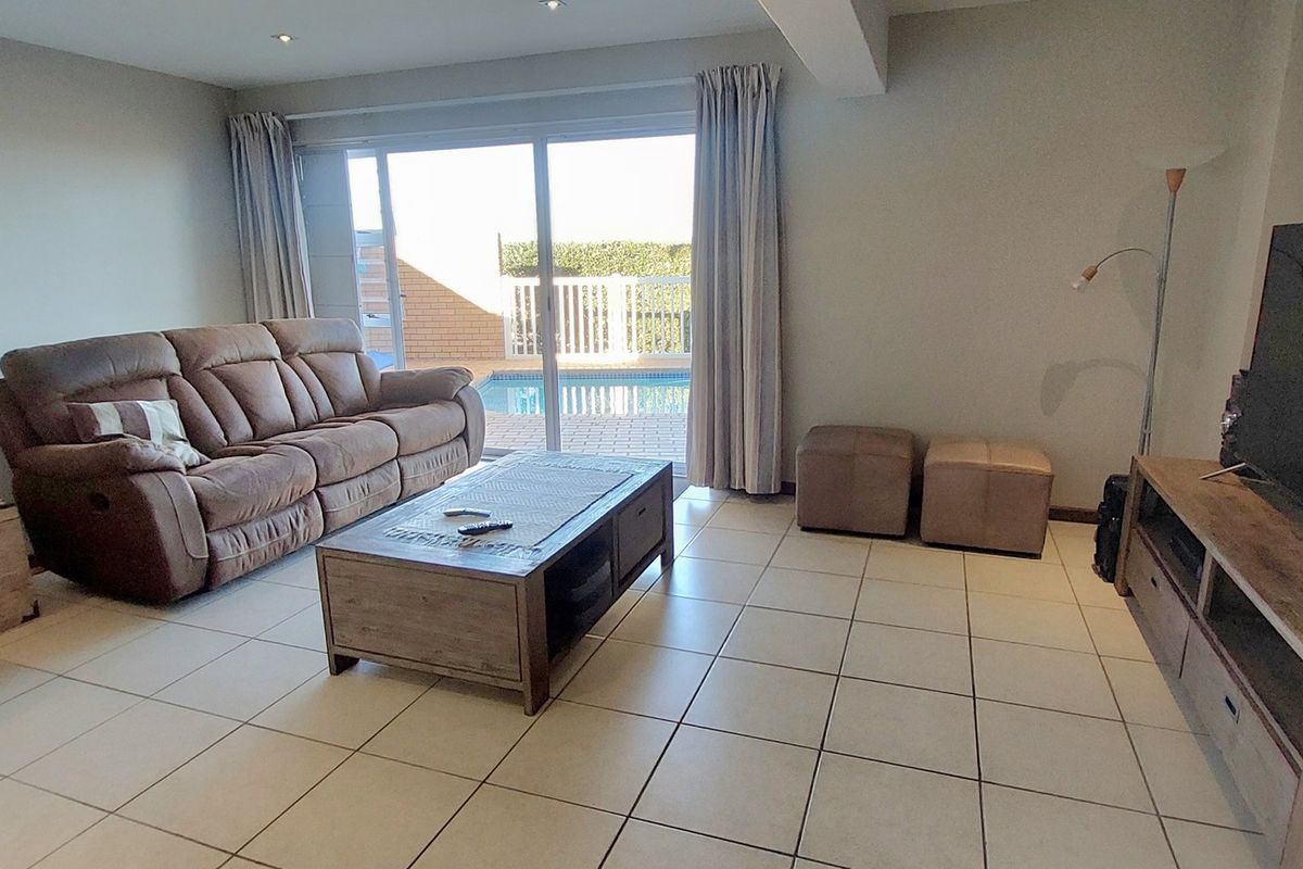 Spacious living room featuring tiled flooring and large sliding glass doors providing direct access to the outdoor pool area.