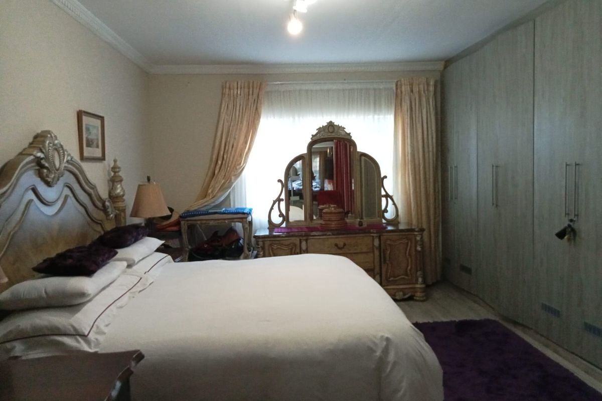 Spacious bedroom featuring extensive built-in floor-to-ceiling cabinetry, decorative ceiling rose, and large window with natural light.