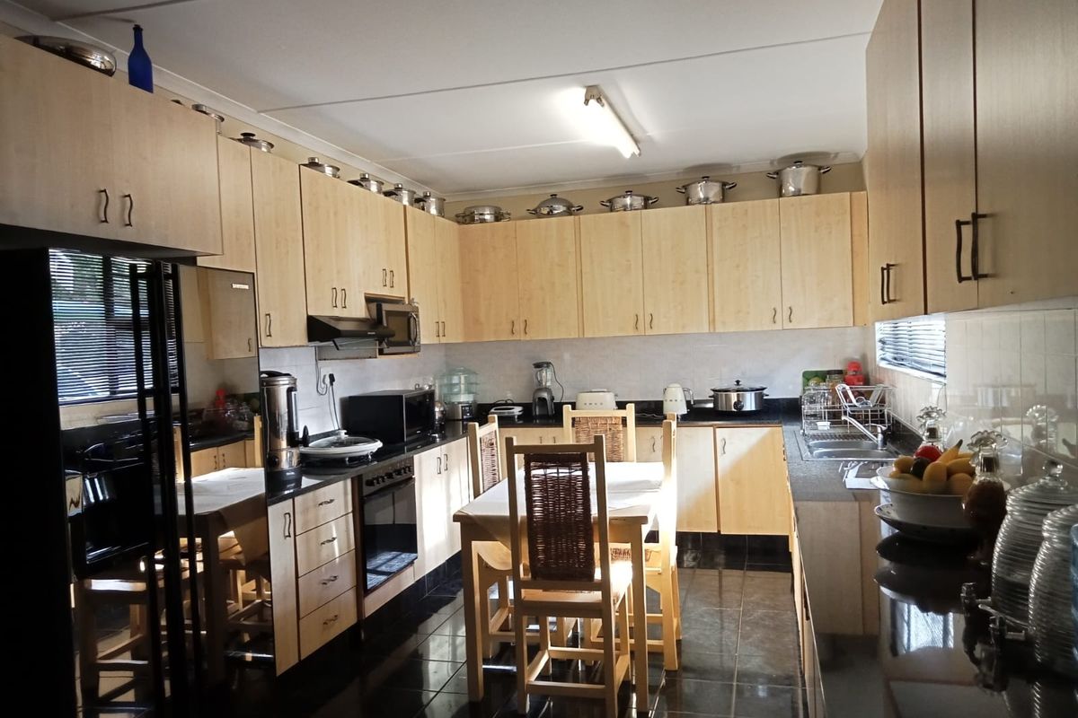 A functional kitchen featuring light wood cabinetry, dark granite countertops, tiled flooring, and integrated appliances, offering ample storage and workspace.