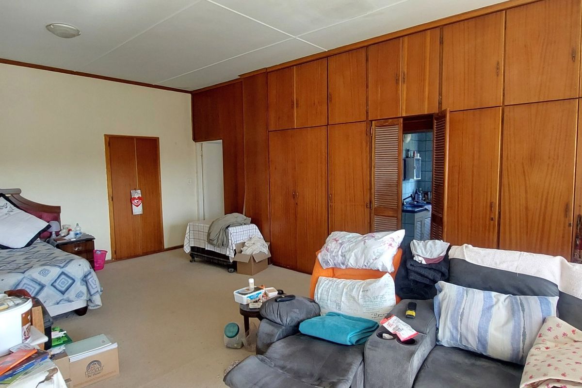 Spacious bedroom featuring extensive floor-to-ceiling built-in wooden cabinetry and neutral carpeting, offering ample storage space.