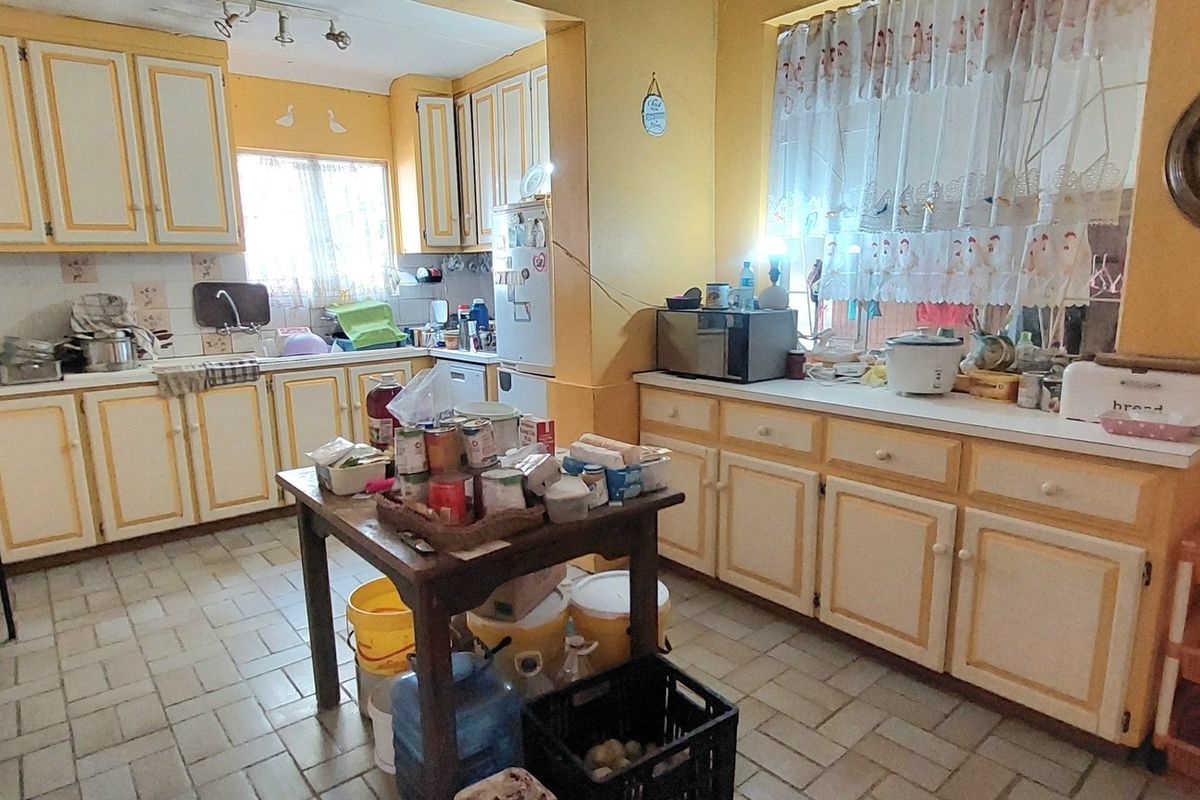 A dated kitchen featuring traditional cabinetry, tiled flooring, and a functional layout with ample counter space, ready for a modern renovation.