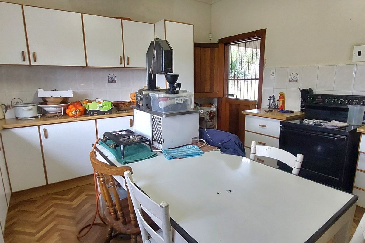A functional kitchen featuring white cabinetry, wood-look laminate countertops, parquet flooring, and a freestanding stove, offering a practical layout for daily meal preparation.