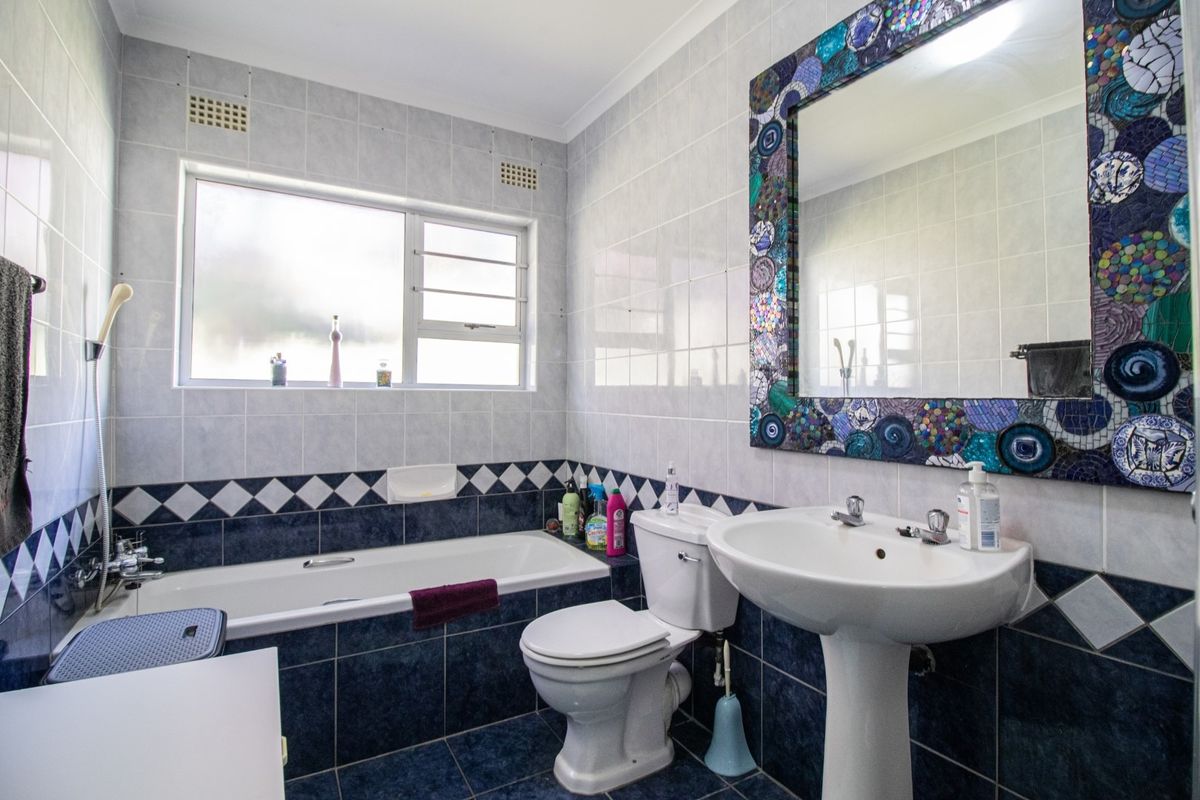 A functional bathroom featuring a bathtub, pedestal basin, and toilet, finished with classic blue and white wall and floor tiling.