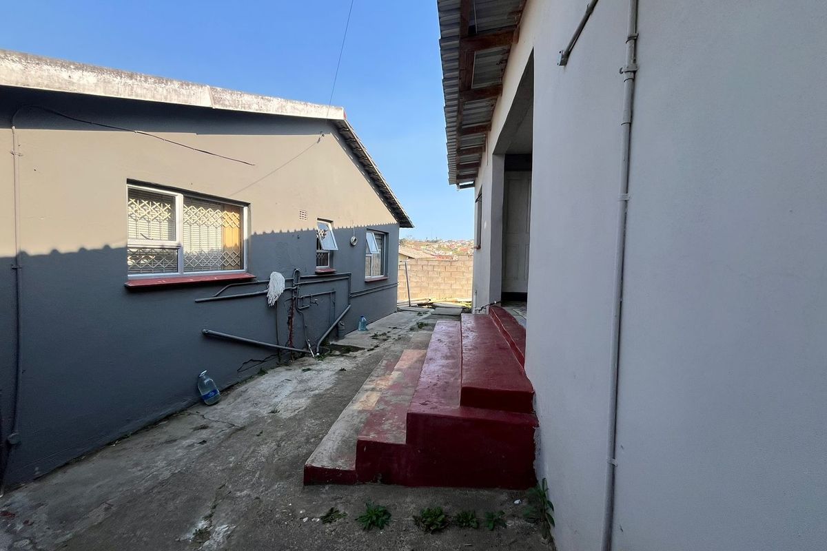 Side exterior view showing concrete pathway, painted steps, and exterior wall finishes between two residential structures.