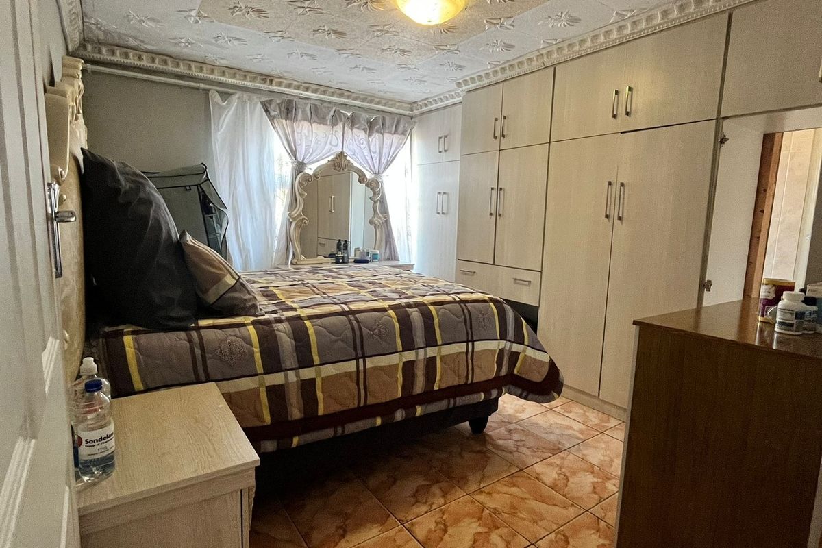 A bedroom featuring built-in floor-to-ceiling cabinetry, tiled flooring, and a decorative textured ceiling.