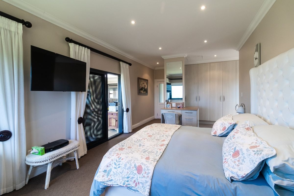 Spacious bedroom featuring built-in cabinetry, a dedicated vanity area, recessed downlighting, and sliding glass doors providing access to an outdoor space.