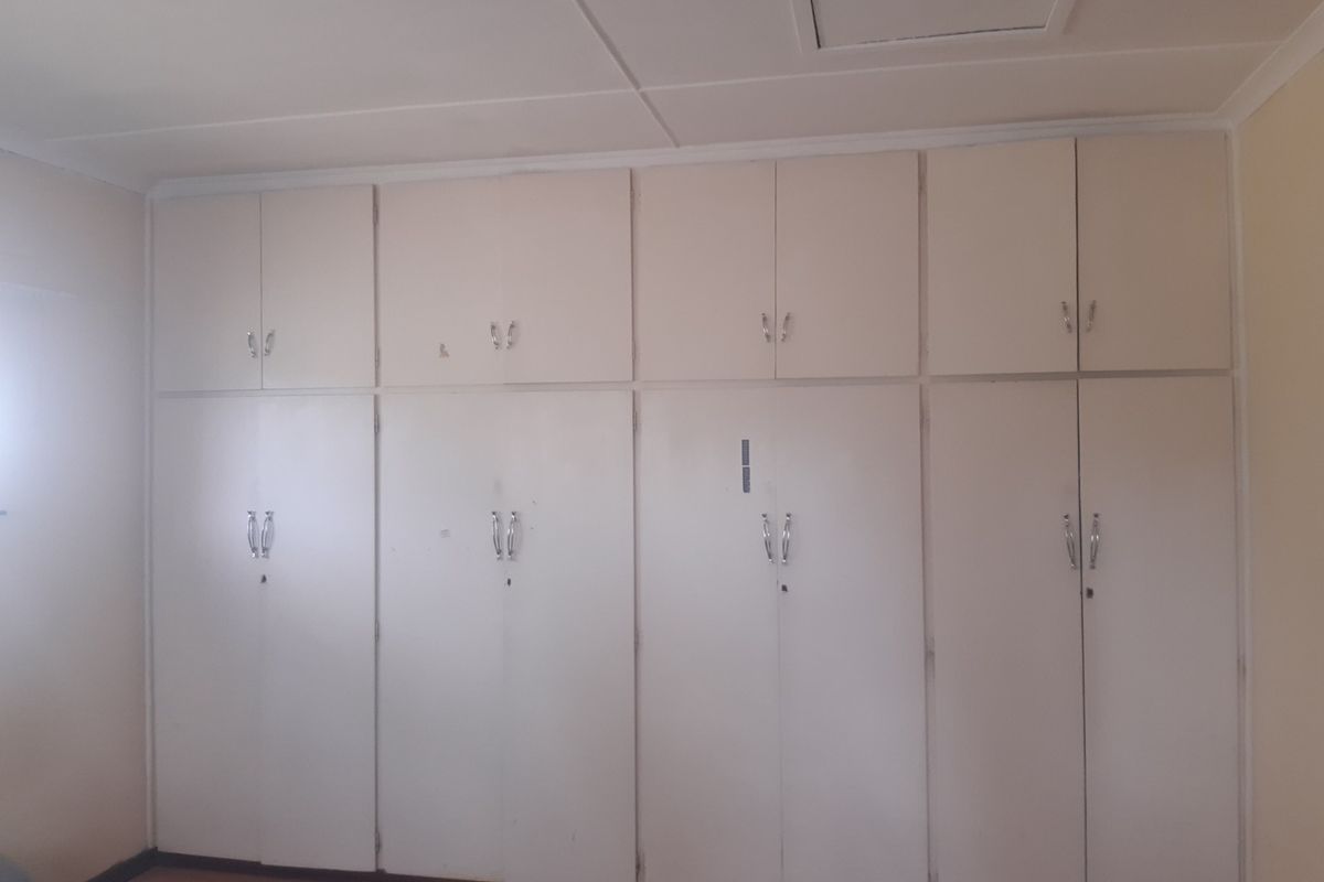 A bedroom featuring extensive floor-to-ceiling built-in cupboards providing ample storage space.