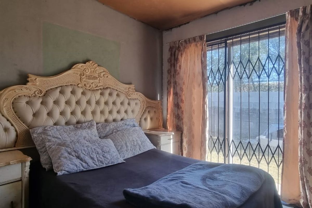 A bedroom featuring a sliding glass door with security gate and access to the exterior, requiring cosmetic updates to walls and ceiling finishes.