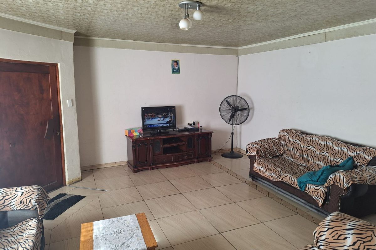 A living room featuring tiled flooring, a textured ceiling, and a solid wood door, providing a functional space for relaxation.