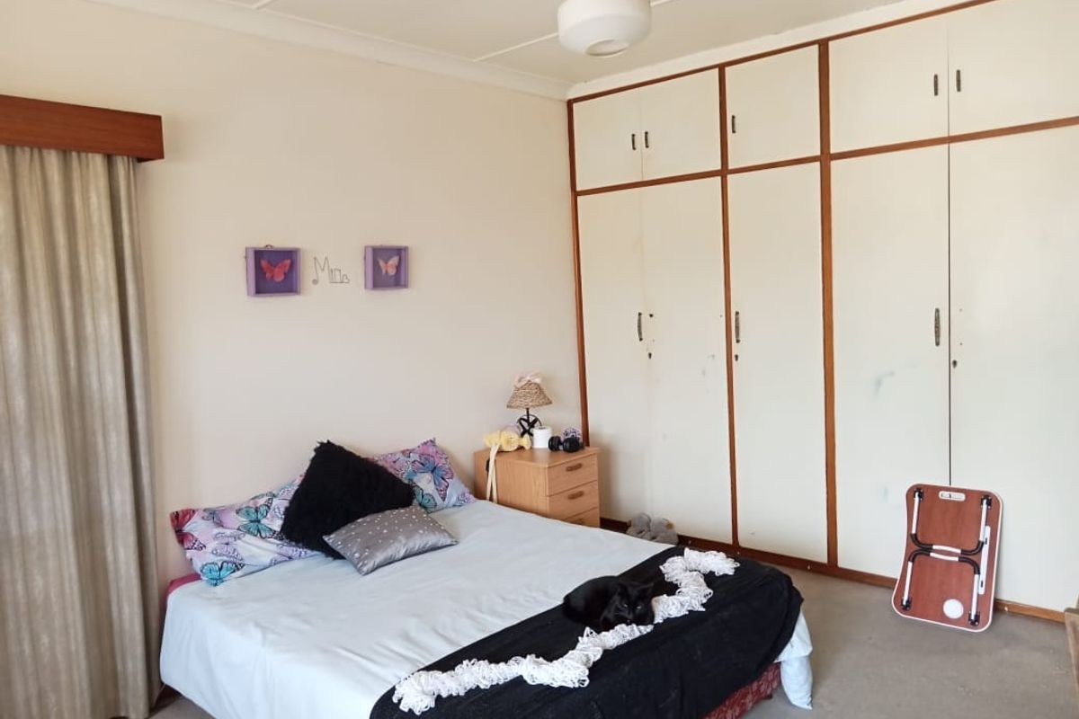A bedroom featuring built-in floor-to-ceiling wardrobes with white panel doors and neutral wall finishes.