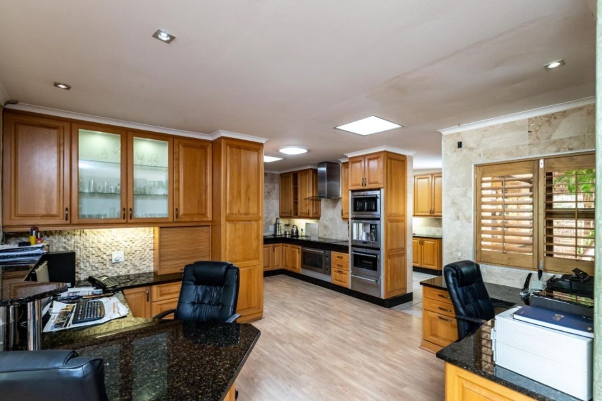 Spacious kitchen featuring extensive wooden cabinetry, granite countertops, built-in stainless steel appliances, and recessed lighting, with a dedicated workspace area.