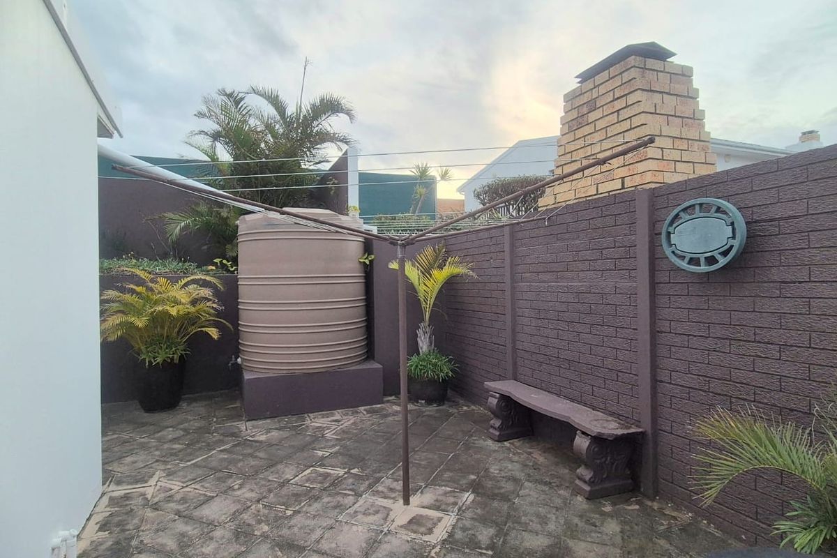 A rear courtyard area featuring a brick chimney, a water storage tank, and paved flooring, providing a functional outdoor utility space.
