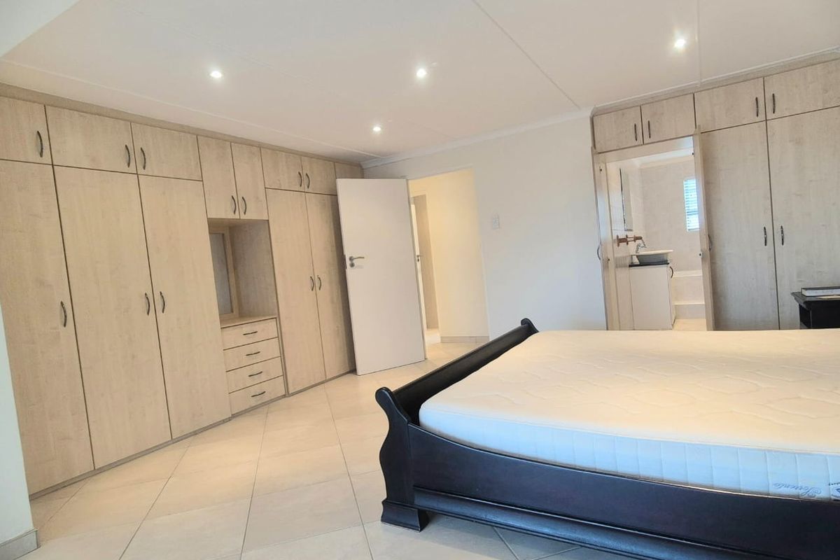 Spacious bedroom featuring extensive built-in cabinetry, tiled flooring, recessed ceiling lighting, and an en-suite bathroom access.