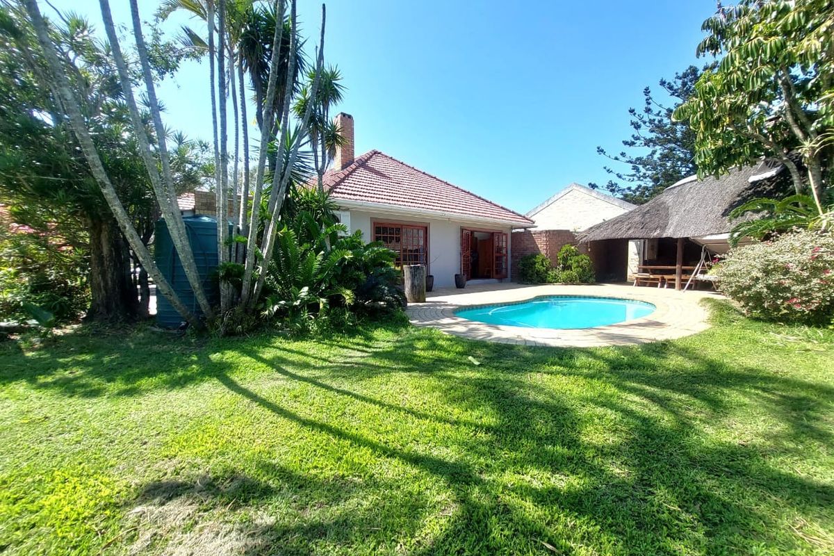 A spacious rear garden featuring a swimming pool, a thatched lapa entertainment area, and established landscaping with a water storage tank.