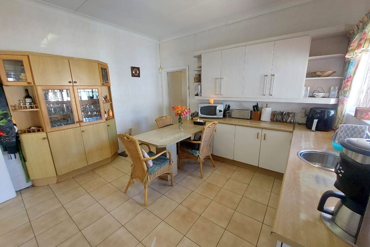 A functional kitchen featuring white cabinetry, laminate countertops, tiled flooring, and an integrated dining area, offering a practical layout for daily use.