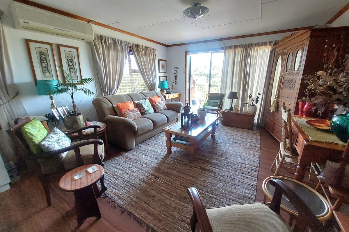 A comfortable living room featuring wood-look flooring, a wall-mounted air conditioning unit, and sliding glass doors providing access to an outdoor area.
