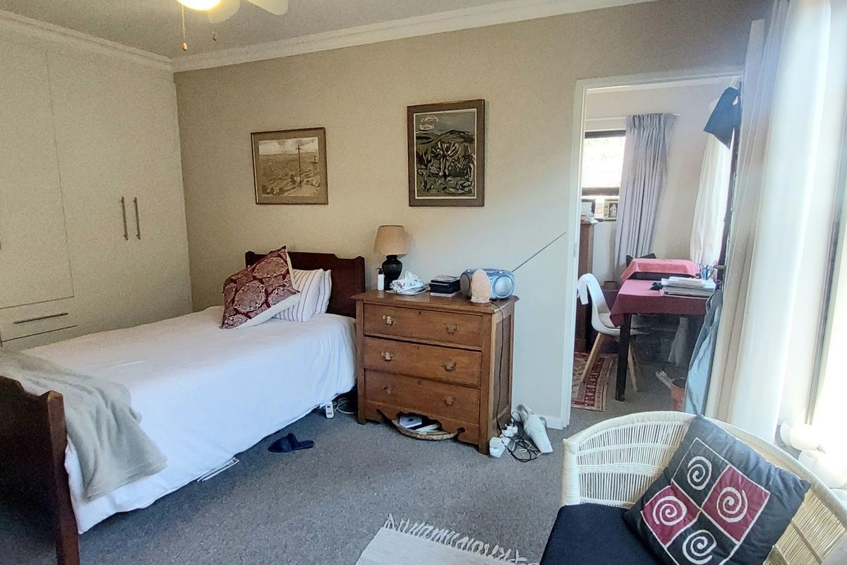 A bedroom featuring built-in floor-to-ceiling wardrobes, neutral carpeting, and a large window providing natural light and access to an outdoor area.