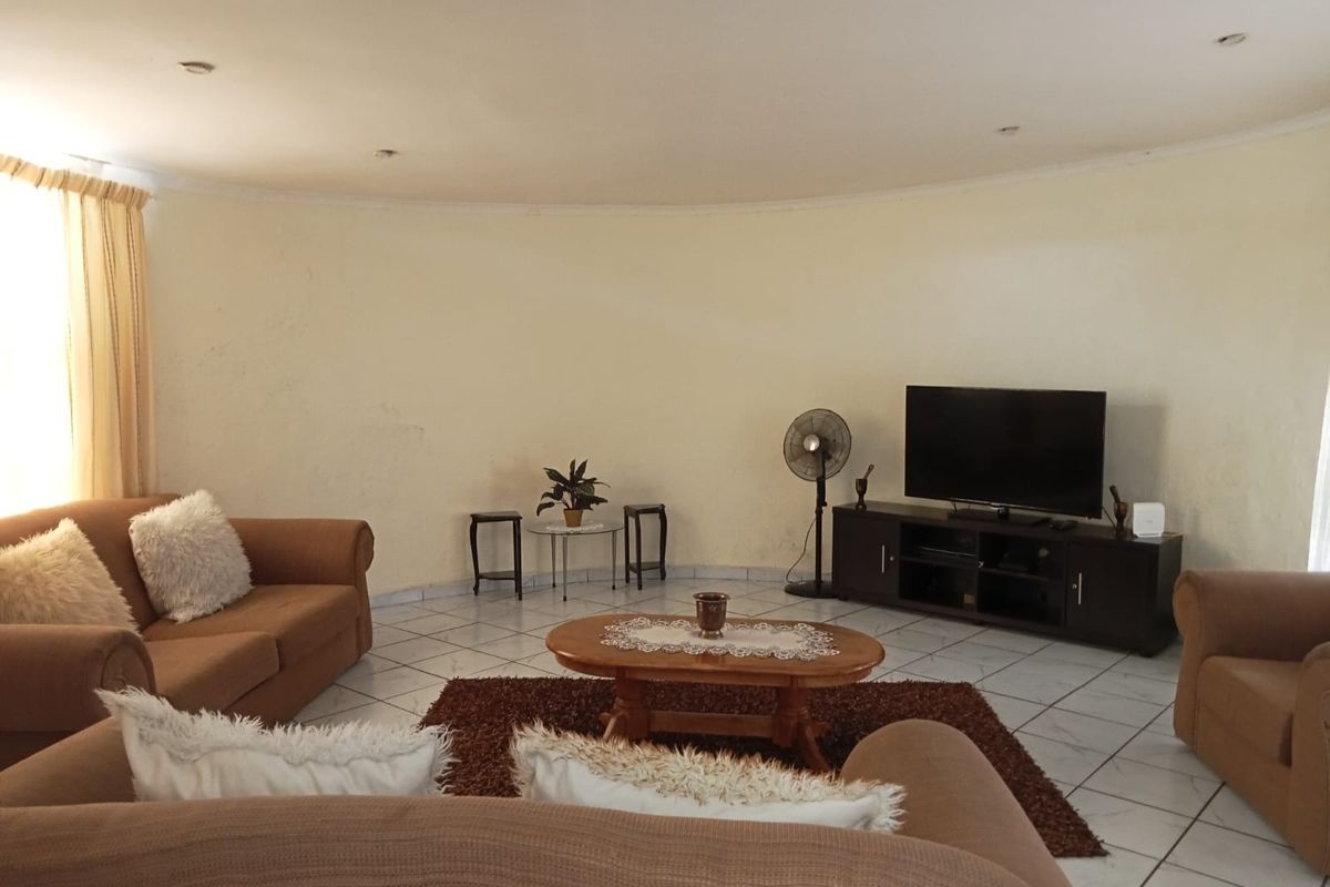 A spacious living room featuring a curved wall design, tiled flooring, and recessed ceiling lighting.